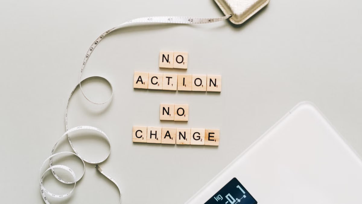 Motivational concept with scrabble tiles spelling no action no change alongside a measuring tape and scale.
